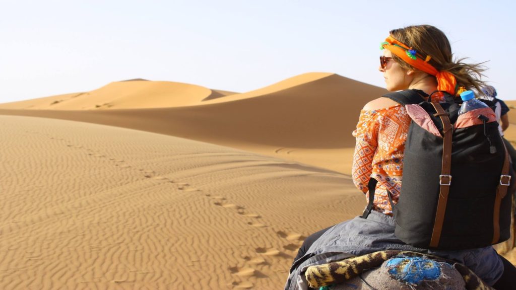 woman riding camel in sand dunes