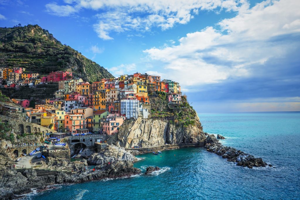 Colorful buildings perched on a rocky cliff overlooking the sea in Cinque Terre, Italy.