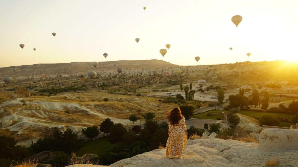 woman looking at a sky full of hot air balloons cappadocia turkey