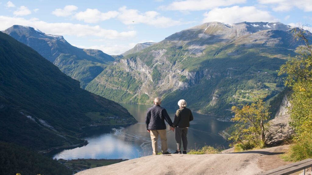 elderly couple holding hands overlooking a fjord Scandinavia