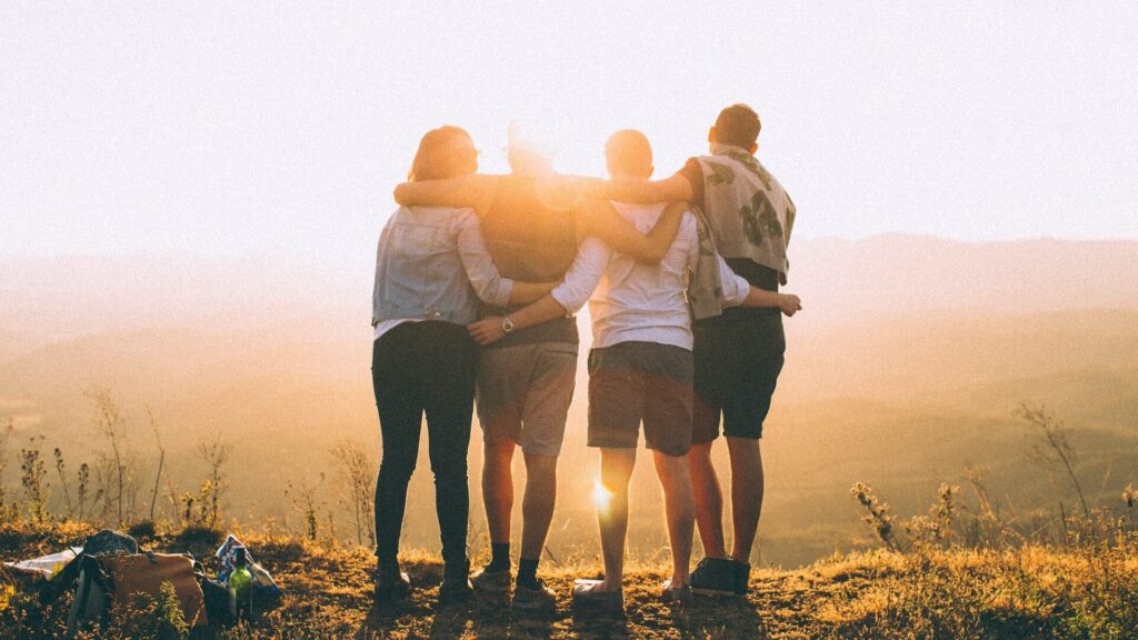 Group of friends hugging, facing sunset