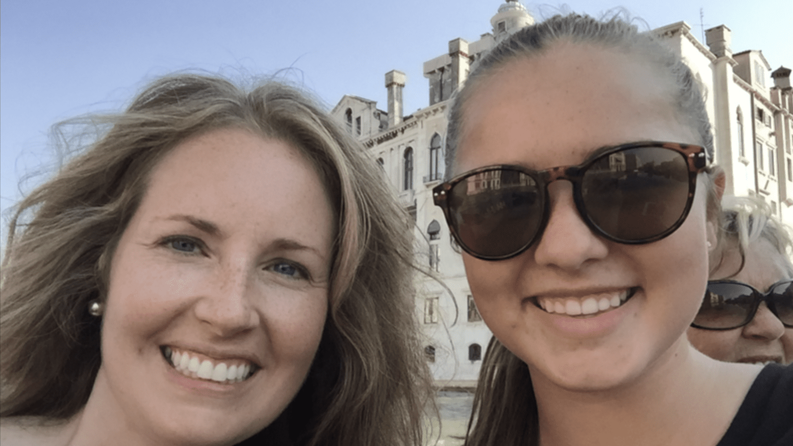 Two females smiling at camera, one wearing sunglasses