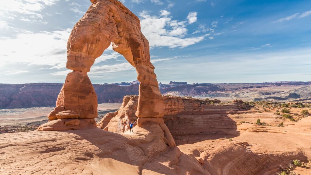Hiker under sandstone arch, arches national park, Utah