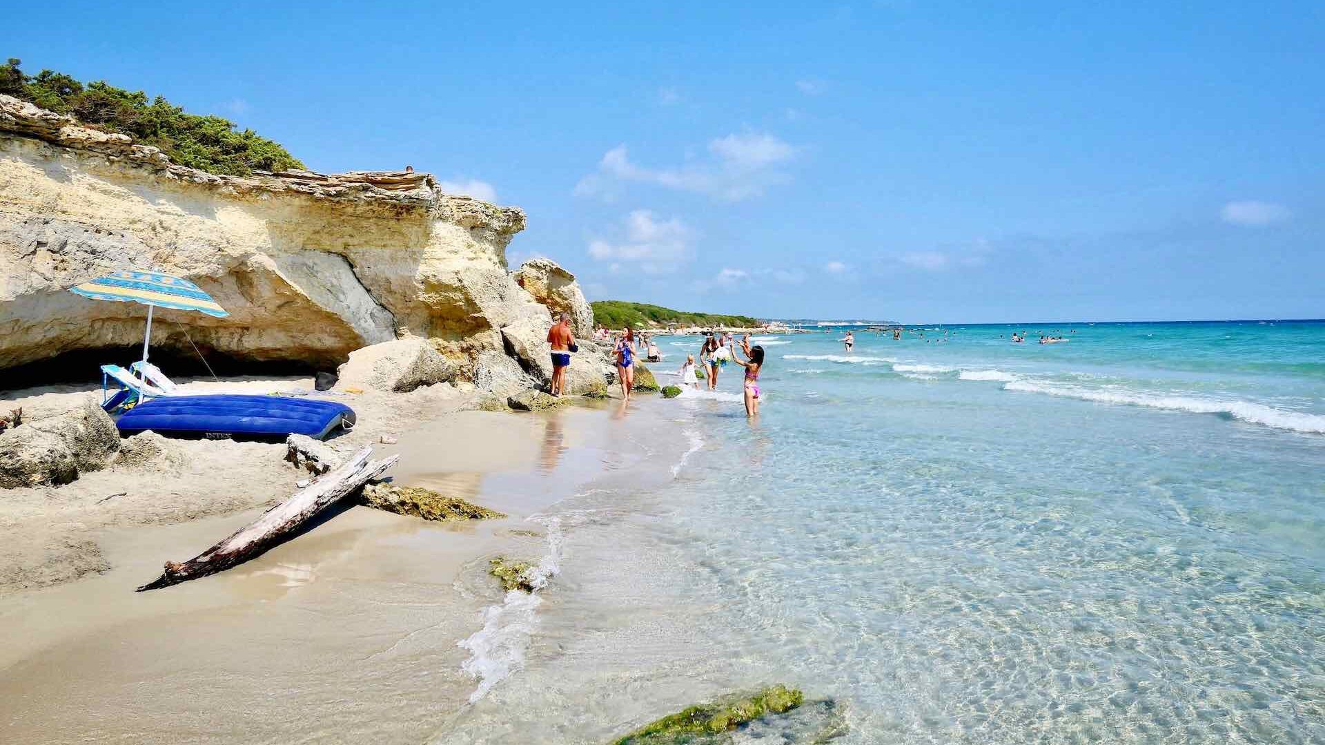 Sun loungers and people on beach Baia dei Turchi, Otranto, Salento, Puglia, Italy. Italy is one of the best beach destinations in Europe.