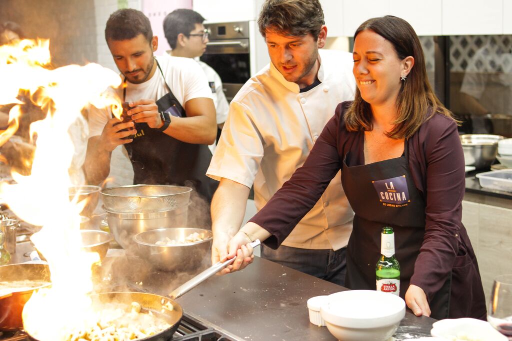 Chef Ignacio helping someone at his cooking school while they fry something on the stove.