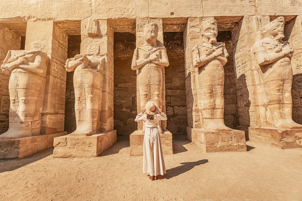Woman looking up at statues outside a temple in Egypt