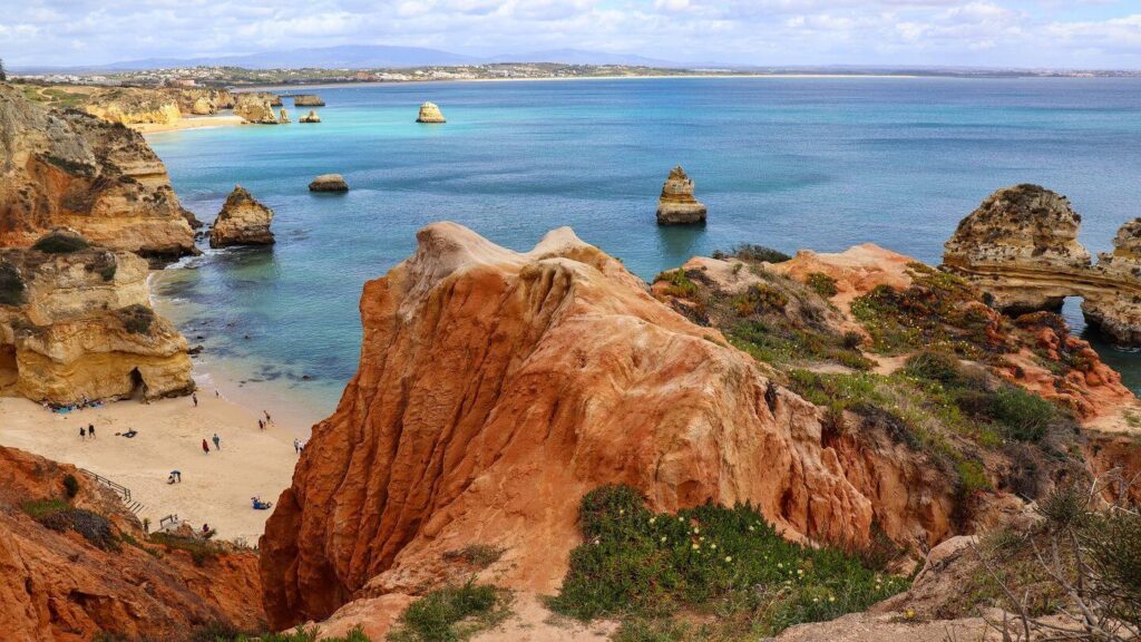 A beach with rocky cliffs and blue water in Portugal.