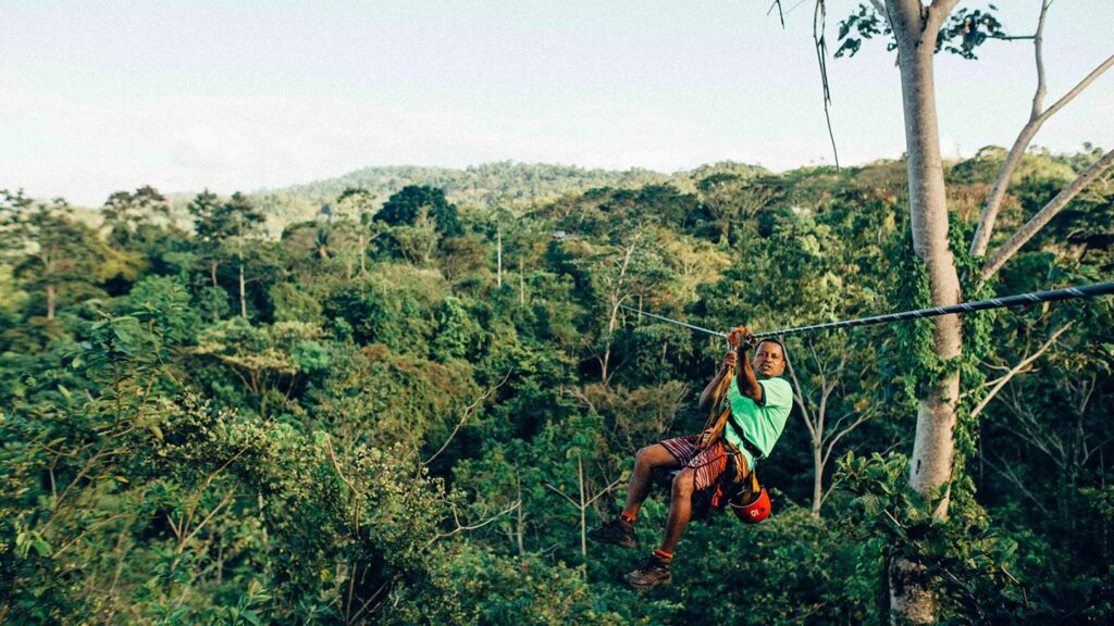 A person ziplining over a lush forest in Costa Rica, wearing safety gear and looking into the distance.