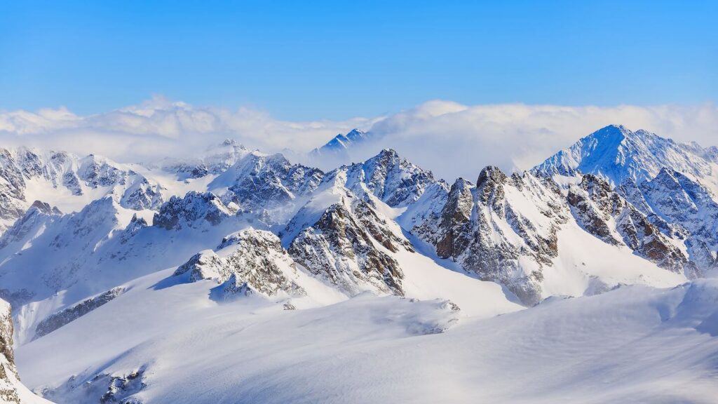 A snow covered mountain range in Switzerland under a blue sky.