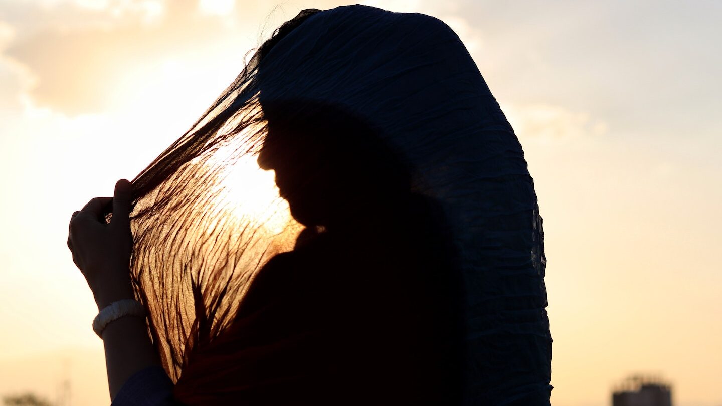 Silhouette of woman in a head scarf