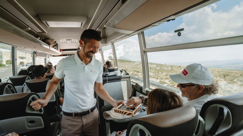Tod inside a Trafalgar coach talking to guests
