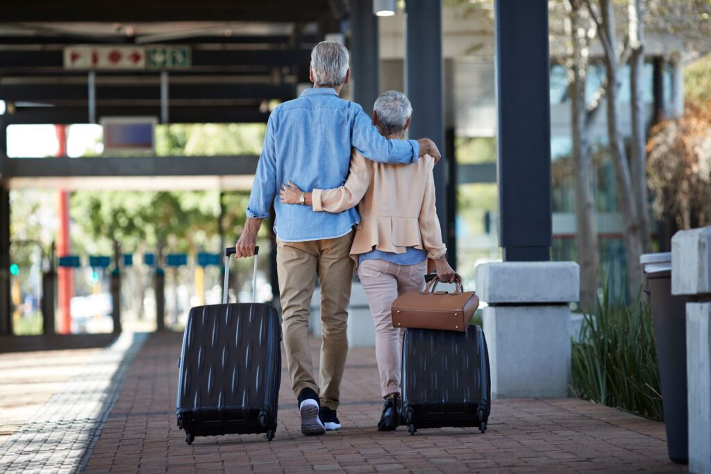 senior couple walking through airport with suitcases