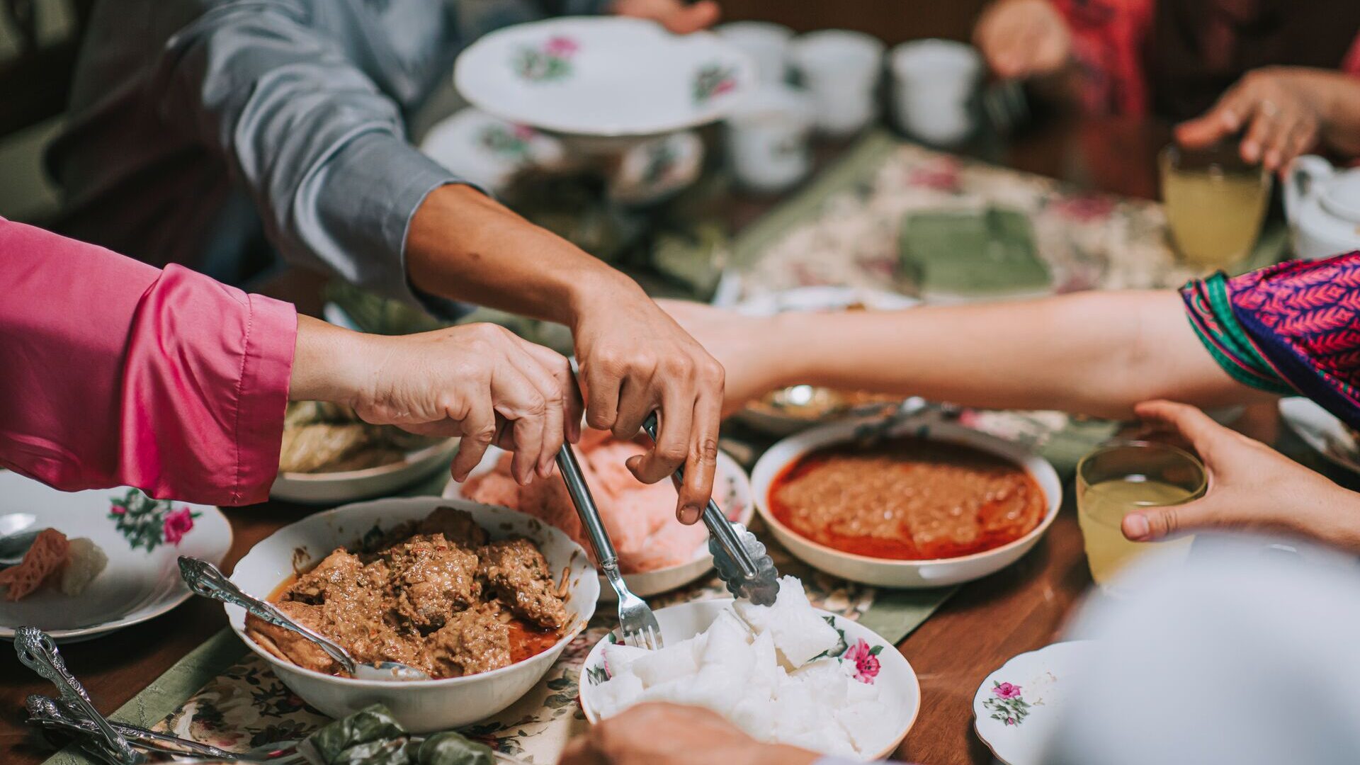 Peoples' hands taking homemade food from bowls on a table 