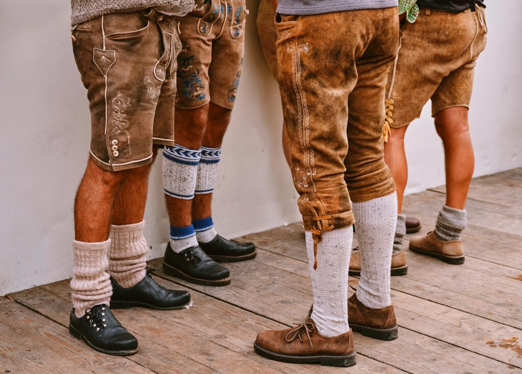 Four men in traditonal German Lederhosen with long socks and leather shoes at Oktoberfest in Munich, Germany